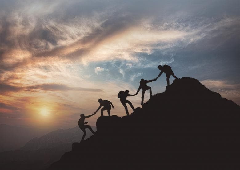 Team climbing mountain at sunset - symbolizing growth and teamwork